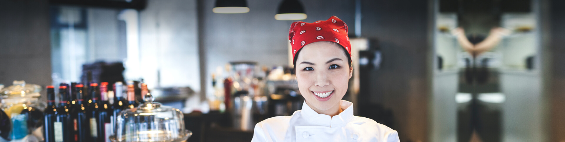 asiatische Frau in Kochkleidung neben Bar